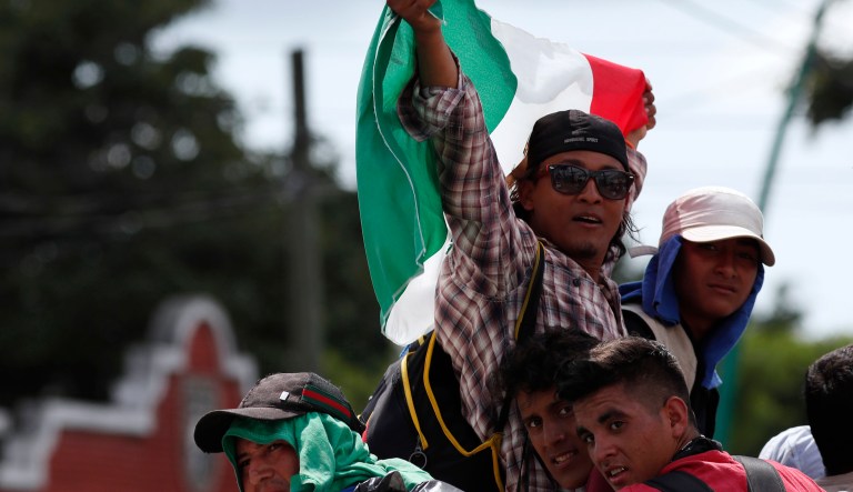 Central American migrants making their way to the U.S. in a large caravan wave a Mexican flag as they arrive to Tapachula, Mexico, after a truck driver gave them a free ride, Sunday, Oct. 21, 2018. 