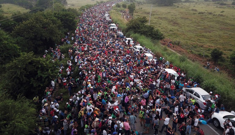 Members of a US-bound migrant caravan stand on a road after federal police briefly blocked their way outside the town of Arriaga, Saturday, Oct. 27, 2018. Hundreds of Mexican federal officers carrying plastic shields had blocked the caravan from advancing toward the United States, after several thousand of the migrants turned down the chance to apply for refugee status and obtain a Mexican offer of benefits.