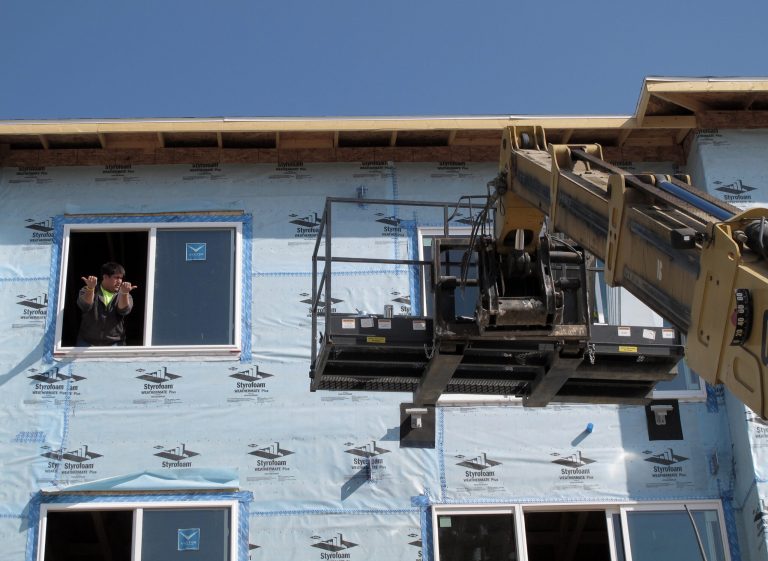 FILE - In this Sept. 25, 2012 file photo, a construction worker signals to the driver of a forklift who is lifting construction materials into place at an apartment construction site in northeast Bismarck, N.D. North Dakota's robust economy lead by its soaring oil production in the western part of the state has resulted record-high home prices and skyrocketing rental prices that reflect tight supply and strong demand statewide.(AP Photo/Dale Wetzel)