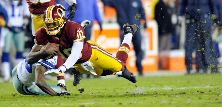 Washington Redskins quarterback Robert Griffin III (10) dives past Dallas Cowboys cornerback Brandon Carr (39) during the first half of an NFL football game Sunday, Dec. 30, 2012, in Landover, Md. (AP Photo/Nick Wass)
