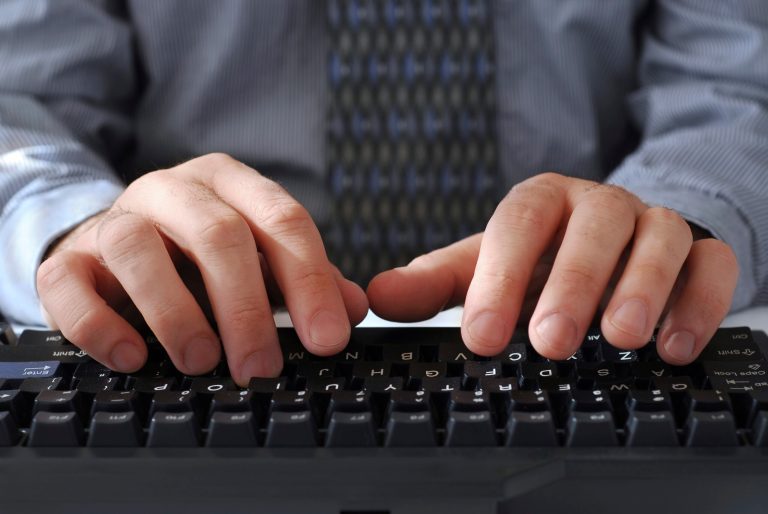 Closeup of man's hands typing on a keyboard