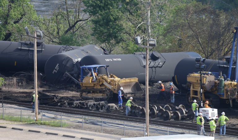 Workers remove damaged tanker cars along the tracks where several CSX tanker cars carrying crude oil derailed and caught fire along the James River near downtown Lynchburg, Va., Thursday, May 1, 2014.  (AP Photo/Steve Helber)