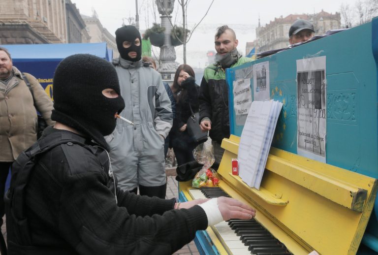 A protester in a balaclava and a flak jacket plays the piano in Kiev's Independence Square, the epicenter of the country's current unrest, Ukraine, Friday, Feb. 14, 2014. A Ukrainian opposition group says that all the protesters detained during nearly three months of opposition demonstrations have been released under an amnesty law. (AP Photo/Efrem Lukatsky)