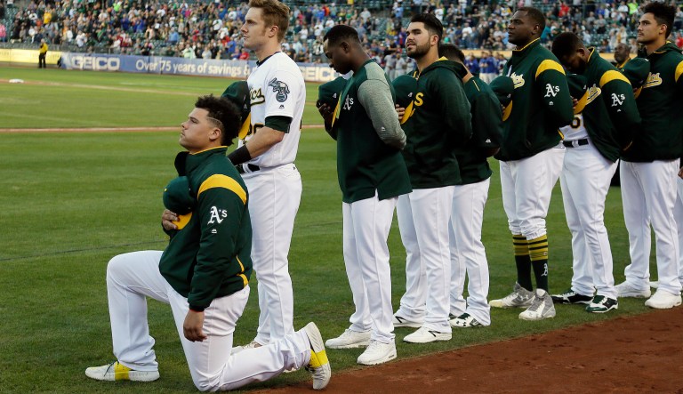 Oakland Athletics catcher Bruce Maxwell kneels during the national anthem before the start of a baseball game against the Texas Rangers Saturday, Sept. 23, 2017, in Oakland, Calif. Bruce Maxwell of the Oakland Athletics has become the first major league baseball player to kneel during the national anthem. (AP Photo/Eric Risberg)