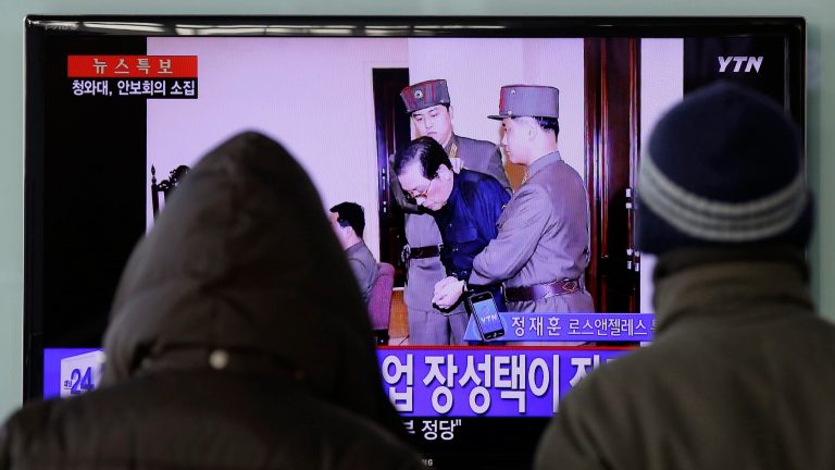 People watch a live TV news program showing that North Korean leader Kim Jong Un's uncle Jang Song Thaek, second from right, is escorted by military officers during a trial in Pyongyang, North Korea Thursday, Dec. 12, 2013, at the Seoul Railway Station in Seoul, South Korea, Friday, Dec. 13, 2013. North Korea said Friday that it had executed Jang as a traitor for trying to seize supreme power, a stunning end for the leader's former mentor, long considered the country's No. 2 official. The letters on the left top, read 