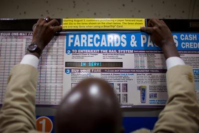 Metro employee Reggie Woodruff puts up temporary information on fare card machines in Faraguett North Metro Station. Metro holds its scheduled fair increase until Tuesday. In Washington, DC on Monday August 3, 2010.
