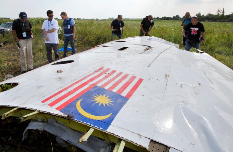 Malaysian investigators along with members of the OSCE mission in Ukraine, examine a piece of the crashed Malaysia Airlines Flight 17 in the village of Petropavlivka, Donetsk region, eastern Ukraine, Wednesday, July 23, 2014. (AP Photo/Dmitry Lovetsky)