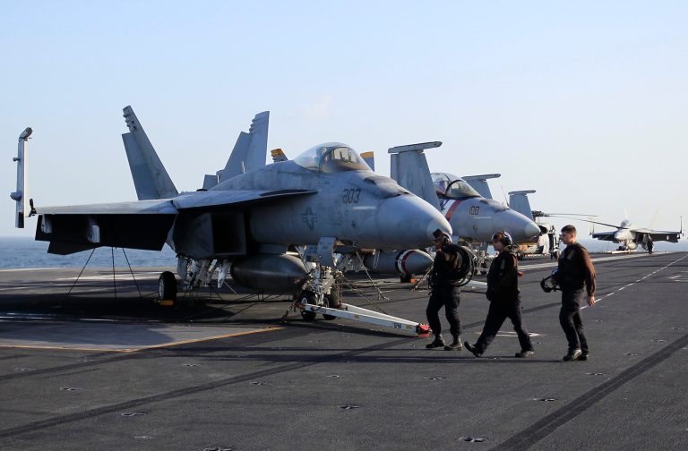 A picture taken on Tuesday, Feb. 14, 2012 shows, plane captains pass by F-18 fighter jets on the flight deck of the Nimitz-class aircraft carrier USS Abraham Lincoln (CVN 72) in the Strait of Hurmuz. The USS Abraham Lincoln sailed from the Persian Gulf through the Strait of Hormuz on Tuesday. (AP Photo/Hassan Ammar)