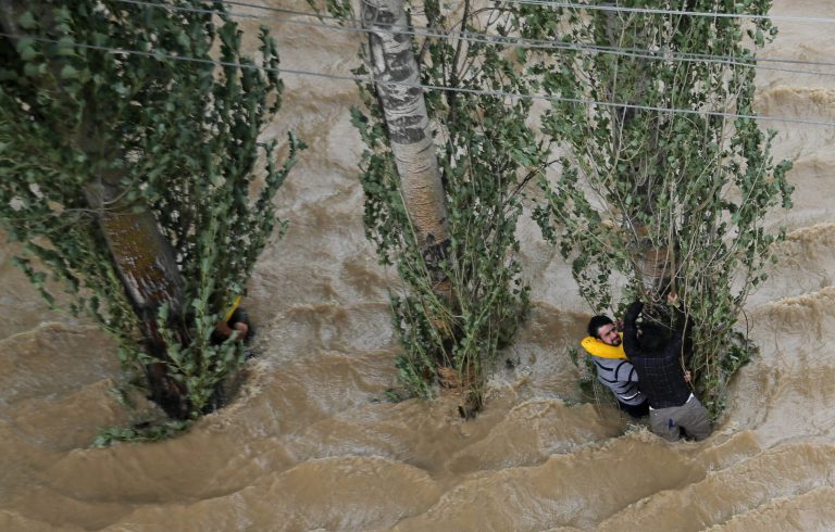 Kashmiris hang on to a tree to prevent being swept away by floodwaters in Srinagar, India, Tuesday, Sept. 9, 2014. The death toll from floods in Pakistan and India reached 400 on Tuesday and have put more than half a million people in peril and rendered thousands homeless in the two neighboring states. (AP Photo/Dar Yasin)