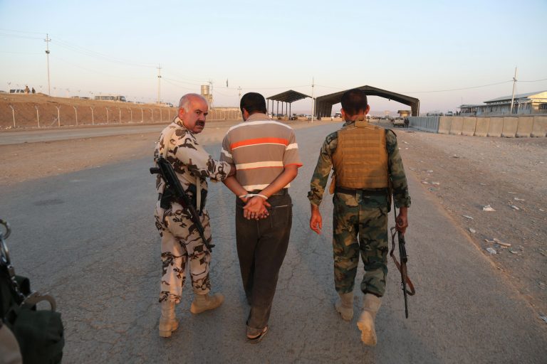 Kurdish Peshmerga fighters detain a man suspected as a militant for the Islamic State group, as airstrikes target Islamic State militants near the Khazer checkpoint outside of the city of Irbil in northern Iraq, Friday, Aug. 8, 2014. (AP Photo/Khalid Mohammed)