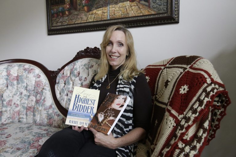 Author Rachel Ann Nunes poses with two versions of her Christian romance novel at her home Tuesday, Sept. 9, 2014, in Orem, Utah. Nunes says a schoolteacher plagiarized her Christian romance novel, added graphic sex scenes and passed it off as her own. In a case she says brings to light plagiarism in the burgeoning world of online self-publishing, Nunes filed a federal lawsuit in August against a Layton, Utah, teacher. Nunes is seeking at least $150,000 in damages as well as attorney's fees in the suit, which was first reported by the Ogden Standard-Examiner. (AP Photo/Rick Bowmer)