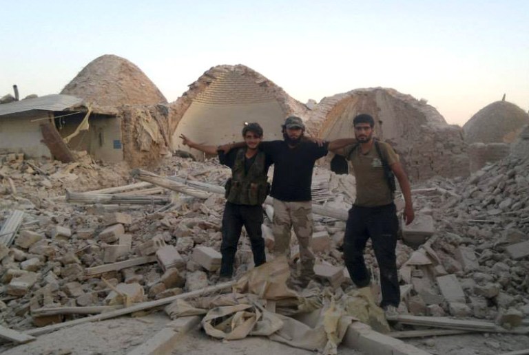Free Syrian army fighters pose for a photograph as they stand in rubble in Idlib province, Syria, on Wednesday. (AP Photo/Aleppo Media Center, AMC)