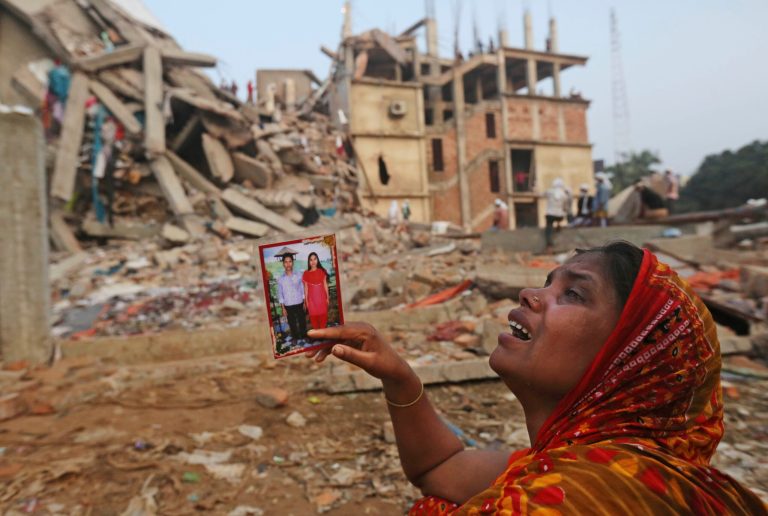 A Bangladeshi woman weeps as she holds a picture of her and her missing husband as she waits at the site of a building that collapsed Wednesday in Savar, near Dhaka, Bangladesh, Friday, April 26, 2013. The death toll reached hundreds of people as rescuers continued to search for injured and missing, after a huge section of an eight-story building that housed several garment factories splintered into a pile of concrete.(AP Photo/Kevin Frayer)