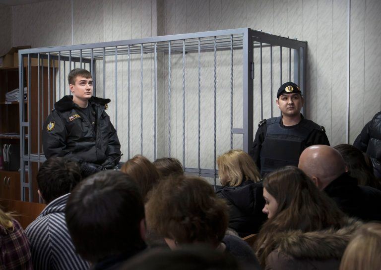FILE - In this Monday, March 11, 2013 file photo, police officers stand near a cage in a courtroom in Moscow, Russia. The European Court of Human Rights has ruled that Russian courts violate the rights of suspects by putting them in metal cages during trial. The court, in a ruling Thursday, July 17, 2014, found that confinement in a metal cage 