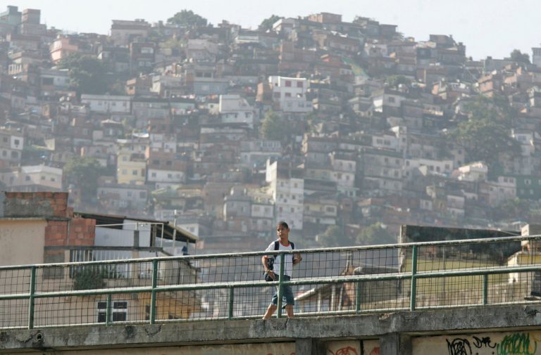 A student crosses a bridge to arrive to his school, with the Rocinha slum visible in the background in Rio de Janeiro, Brazil, on Monday, July 3, 2006. (AP File)