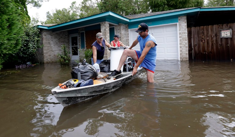 Christopher Tabb, left, with the help of friend Frank Story, center, and nephew Anthony Tabb, right, uses a boat to recover items from his flooded home, Friday, Aug. 31, 2012, in Reserve, La. (AP Photo/Eric Gay)