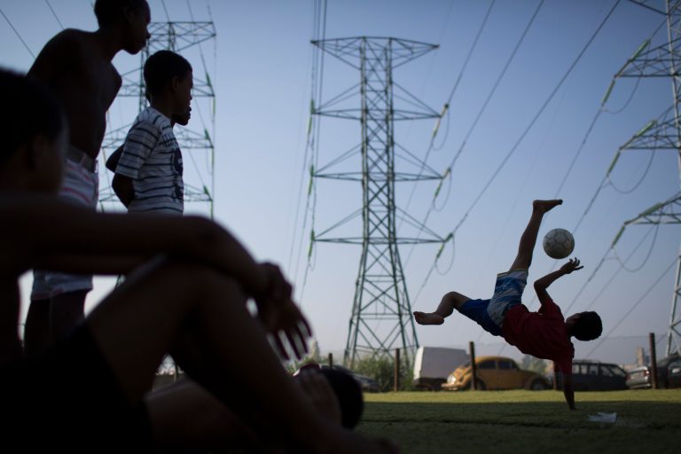 Boys watch as another boy practices his soccer bicycle kicks at a Rio de Janeiro slum, Brazi, Monday, June 9, 2014. The 2014 Word Cup soccer tournament is set to begin in just a few days, with Brazil and Croatia playing in the opening match on June 12. (AP Photo/Felipe Dana)