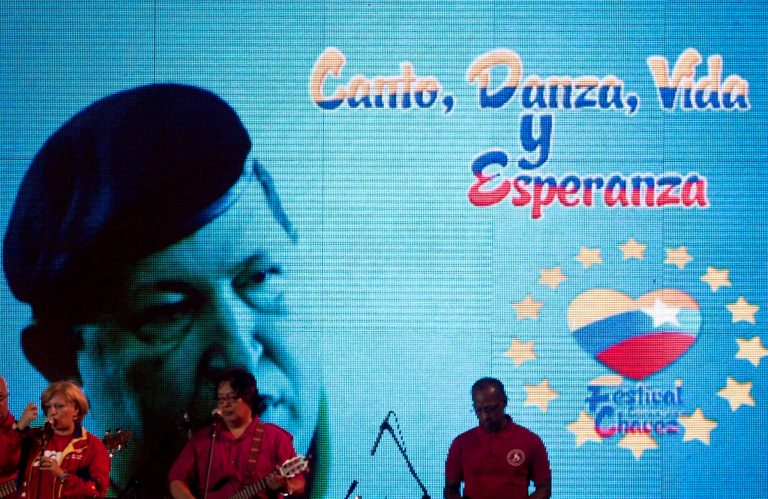   Musicians perform in front of an image of Venezuela's President Hugo Chavez that reads in Spanish 