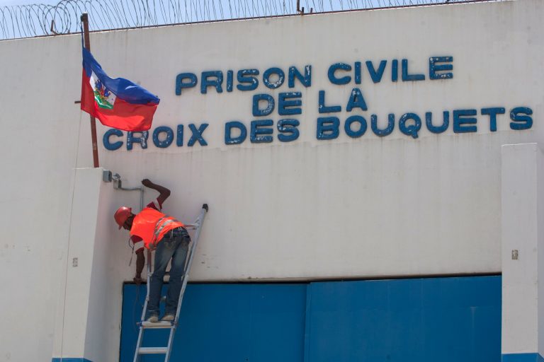 In this Sept. 3, 2014 photo, a technician drills cable for a camera control through the principal gate of the main prison in Croix-des-Bouquets, Haiti. At the prison steps are being taken to improve security. Workers have started to lay down wiring for security cameras at the prison, and officials say they soon will place ankle monitors on the most dangerous inmates there, a plan they say will be implemented in other prisons as well. (AP Photo/Dieu Nalio Chery)