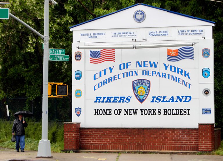 A man walks near the sign at the entrance to the Rikers Island jail in New York. (AP Photo/Seth Wenig)