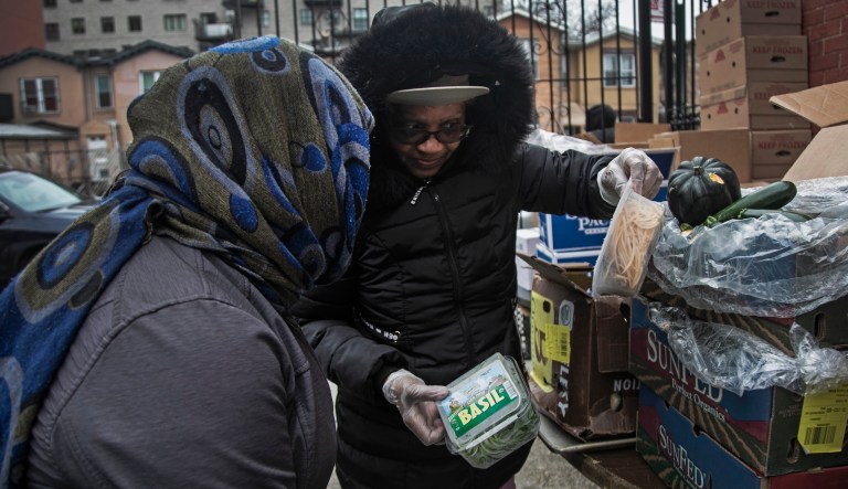 Elaine Peoples 68, right, gives out food donations to a woman at St. Stephen Outreach in the Brooklyn borough of New York, on Friday, March 20, 2020. For more than a week, Elaine Peoples, who cooked for a now-shuttered daycare center, has been out of work.