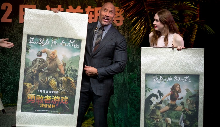 American actor Dwayne Johnson, left, and British actress Karen Gillan hold movie posters created in the style of Chinese scroll art during a press conference for the movie 'Jumanji: Welcome to the Jungle' in Beijing, Thursday, Jan. 4, 2018.