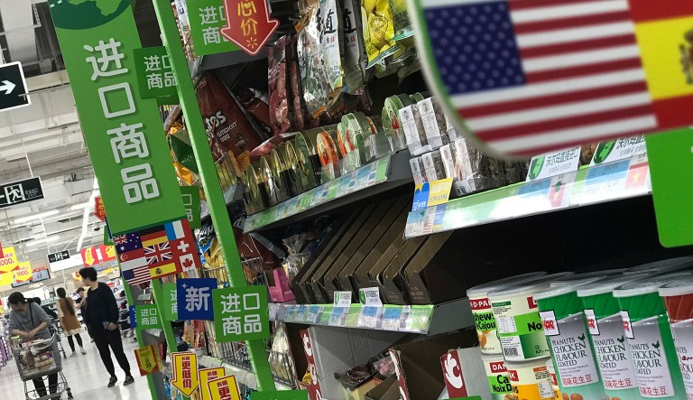Women push a shopping cart near nuts and sweets imported from the United States and other countries displayed on a section selling imported foods at a supermarket in Beijing, Monday, April 2, 2018. China raised import duties on a $3 billion list of U.S. pork, fruit and other products Monday in an escalating tariff dispute with President Donald Trump that companies worry might depress global commerce.
