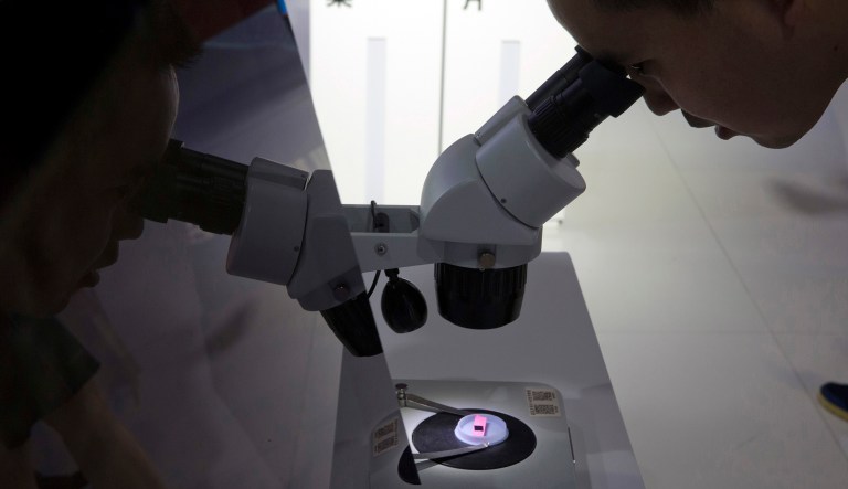 A visitor to the 21st China Beijing International High-tech Expo looks at a computer chip through the microscope displayed by the state-controlled Tsinghua Unigroup project which has emerged as a national champion for Beijing's semiconductor ambitions in Beijing, China, Thursday, May 17, 2018. The Trump administration has threatened to impose tariffs on up to $150 billion in Chinese imports to punish Beijing over trade practices requiring American companies to hand over technology in exchange for access to the Chinese market. China has counterpunched by targeting $50 billion in U.S. products.