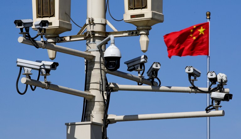 A Chinese national flag flutters near the surveillance cameras mounted on a lamp post in Tiananmen Square in Beijing, Friday, March 15, 2019. 