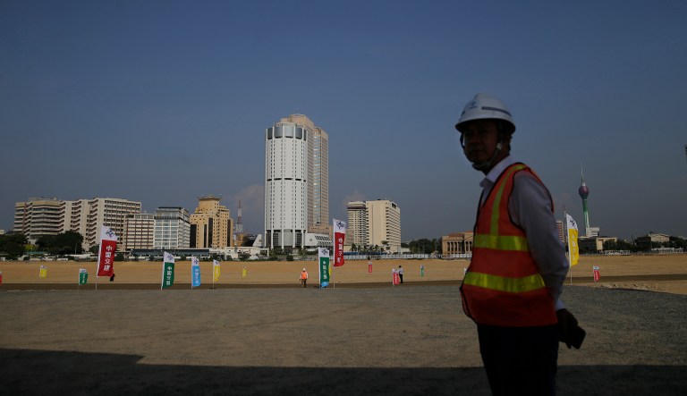 A Chinese construction worker stands on the land that was reclaimed from the Indian Ocean for the Colombo Port City project, on the Galle Face sea promenade in Colombo, Sri Lanka, Tuesday, Jan. 2, 2018. The Port City project was initiated as part of China's ambitious One Belt One Road initiative which envisages linking China's economic centers with energy-rich Persian Gulf along the ancient silk road. China invests US $ 1.4 billion in the project which involves the reclamation of land off the coast of Sri Lanka's capital Colombo for a 269 hectare (664 acre) artificial city that will include an international financial district, living and entertainment areas.