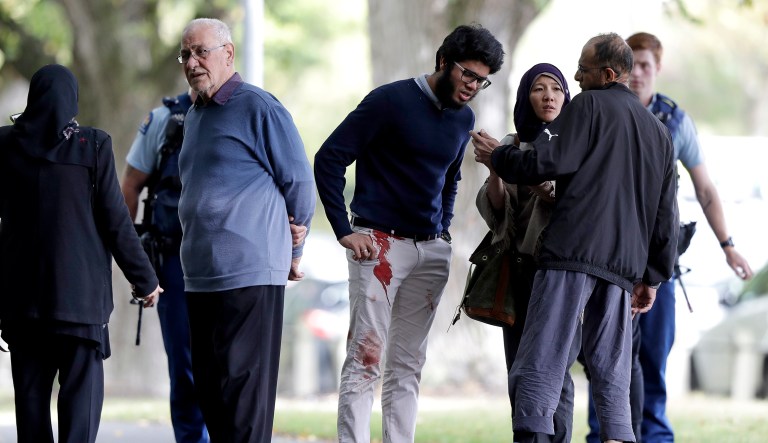 People stand across the road from a mosque in central Christchurch, New Zealand, Friday, March 15, 2019. A witness says a number of people have been killed in a mass shooting at a mosque in the New Zealand city of Christchurch; police urge people to stay indoors.