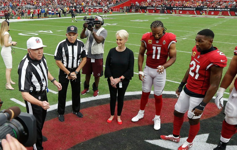 Cindy McCain, wife of the late U.S. Sen. John McCain, R-Ariz., stands with Arizona Cardinals players' Larry Fitzgerald (11) and Patrick Peterson (21) as an honorary team captain during the coin toss prior to an NFL football game against the Washington Redskins, Sunday, Sept. 9, 2018, in Glendale, Ariz. (AP Photo/Ross D. Franklin, Pool)