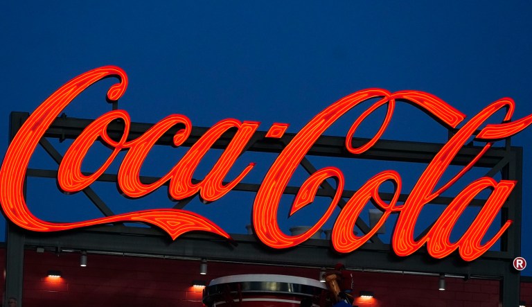 A sign advertising for Coca-Cola shines over the outfield at Truist Park during a baseball game between the Philadelphia Phillies and the Atlanta Braves Monday, April 12, 2021, in Atlanta.