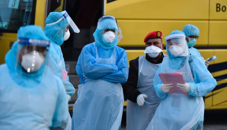 This handout photo taken and released  by Malaysia's Ministry of Health shows health officials in protective suits at the Kuala Lumpur International Airport in Sepang, Malaysia, Tuesday, Feb. 4, 2020, waiting for arrivals that were evacuated from China's Wuhan, the epicenter of the novel coronavirus outbreak. 