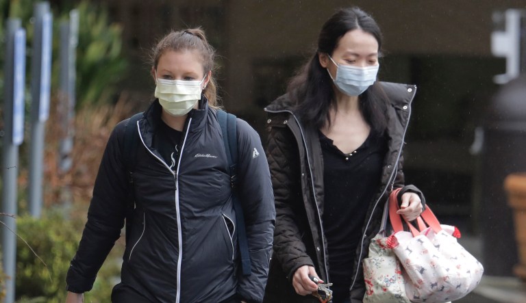 Two women wearing masks walk away from the Life Care Center in Kirkland, Wash., near Seattle, Monday, March 2, 2020. Health officials in Washington state said Sunday night that a second person had died from the coronavirus.