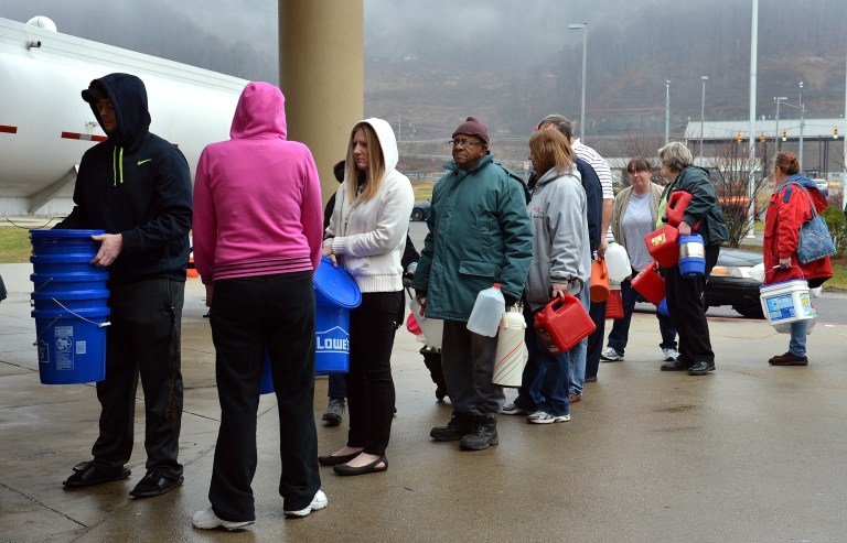 People wait in line for water from a tanker truck on Friday at Riverside High School near Charleston, W.Va., after a chemical spill left the water for 300,000 people in and around West Virginia's capital city stained blue-green and smelling like licorice. (AP Photo/The Daily Mail, Craig Cunningham)