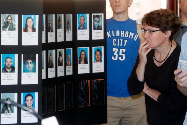 Susan White looks over booking photos displayed at a Vermont State Police news conference to discuss the arrest of 36 people in the area as part of a large drug sweep. (AP/Toby Talbot)