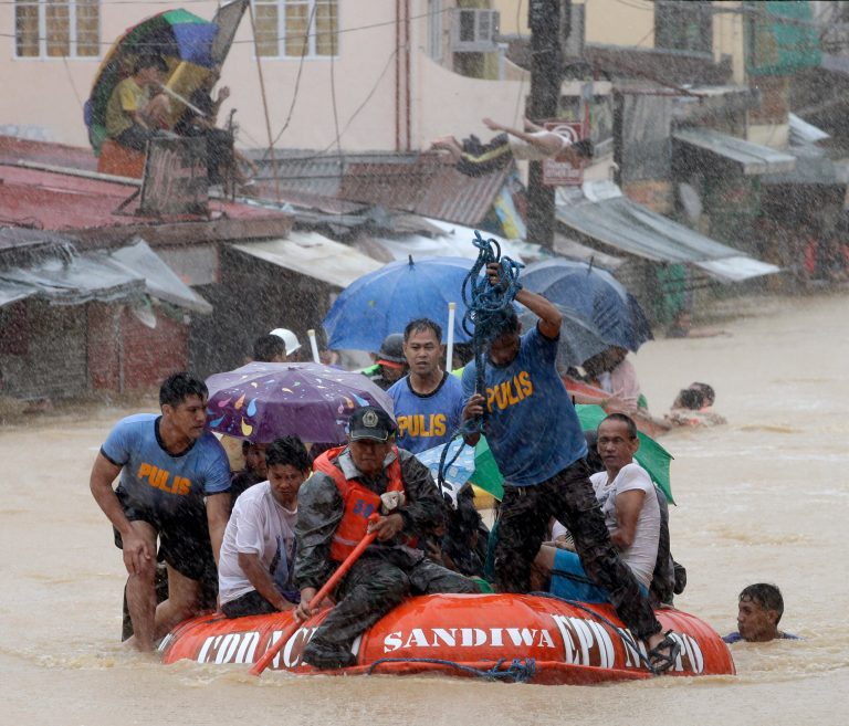 A man dives in the background as rescuers use a rubber dinghy to rescue trapped residents after continues heavy monsoon rains spawned by tropical storm Fung-Wong flooded Marikina city, east of Manila, Philippines and most parts of  the metropolis Friday, Sept. 19, 2014. Heavy rains due to a storm and the seasonal monsoon caused widespread flooding Friday in the Philippine capital and nearby provinces, shutting down schools and government offices. Local authorities reported thousands were evacuated early Friday from severely inundated communities, some under rapid-flowing flood waters more than neck high.(AP Photo/Bullit Marquez)