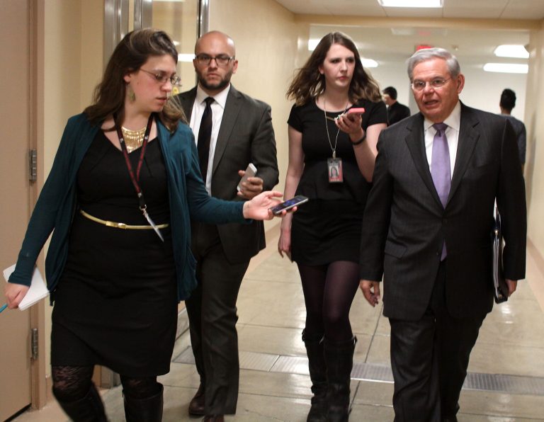 Sen. Bob Menendez, D-N.J., right, is pursued by reporters on Capitol Hill in Washington, Wednesday, Feb. 25, 2015. Menendez, D-N.J., and several other Democrats objected to the timing of a measure that would require Obama to submit to Congress the text of any deal with Iran for approval. (AP Photo/Lauren Victoria Burke)