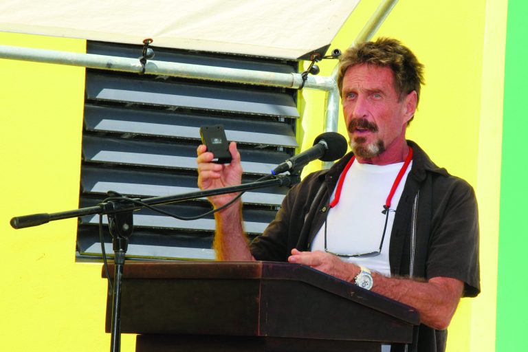 FILE -In this Thursday Nov. 8, 2012 file photo software company founder John McAfee speaks at the official presentation of equipment ceremony that took place at the San Pedro Police Station in Ambergris Caye, Belize. Software company founder John McAfee said Tuesday, Nov. 20, 2012, he's wearing a disguise and hiding in plain sight, watching police and reporters stake out his home and blogging about it. (AP Photo/Ambergris Today Online-Sofia Munoz, File)