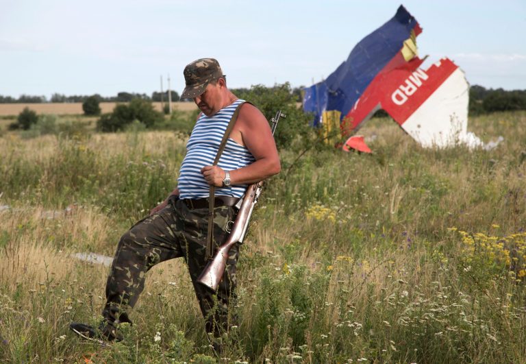 A pro-Russian fighter walks past a piece of the crashed Malaysia Airlines Flight 17 near the village of Hrabove, eastern Ukraine Monday, July 21, 2014. Four days after Flight 17 was shot out of the sky, international investigators still have had only limited access to the crash site, hindered by pro-Russia fighters who control the verdant territory in eastern Ukraine. Outrage over the delays and the possible tampering of evidence at the site was building worldwide, especially in the Netherlands, where most of the victims were from.  (AP Photo/Dmitry Lovetsky)
