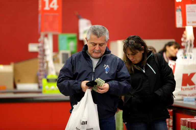 In this  Thursday, Nov. 28, 2013, photo, a man sorts through cash after checking out at a Kmart, in New York.  The Commerce Department reports how much consumers spent and earned in October on Friday, Dec. 6, 2013.  (AP Photo/Julio Cortez)