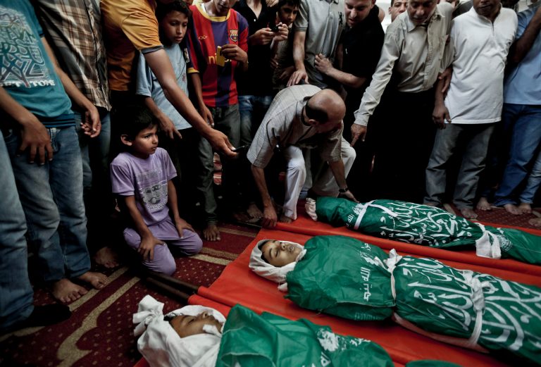 Palestinian mourners gather around the bodies of three siblings of the Abu Musallam family during their funeral in Beit Lahiya, northern Gaza Strip, Friday, July 18, 2014. Ismail Abu Musallam said three of his children: Ahmed, 11; Walaa, 14, and Mohammed, 16, were in bed when an Israeli shell slammed into the home, burying them under debris. His personal tragedy is not unique: minors make up almost one-fifth of those killed in Israel's 11-day bombardment of Hamas targets in densely populated Gaza, where half the population is under the age of 18.  (AP Photo/Lefteris Pitarakis)