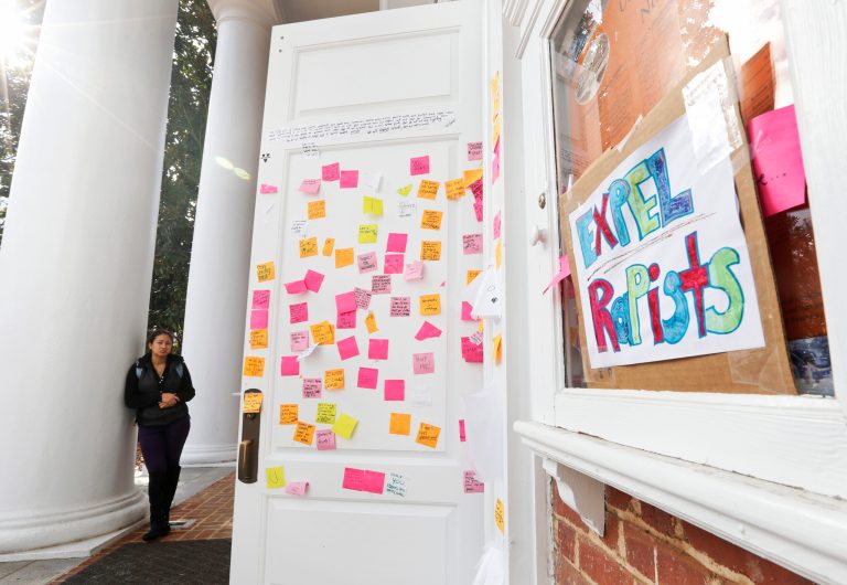 A University of Virginia student looks over postings on the door of Peabody Hall related to the Phi Kappa Psi gang rape allegations at the school in Charlottesville, Va., Monday, Nov. 24, 2014. (AP Photo/Steve Helber)
