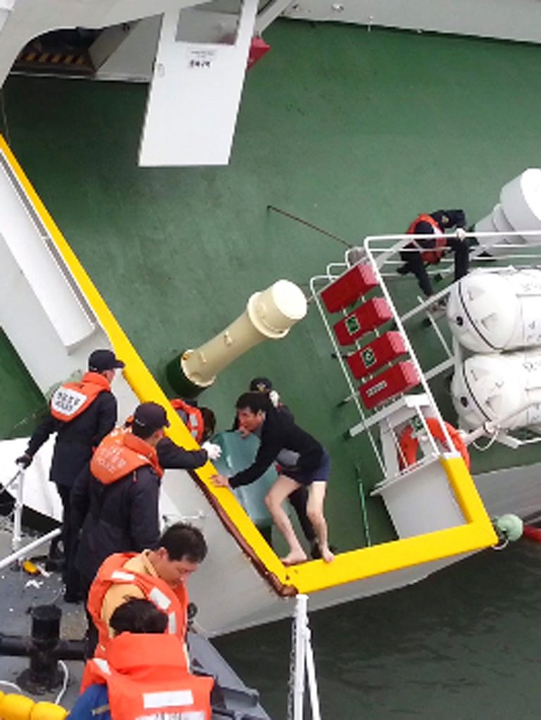In this April 16, 2014 photo released by South Korea Coast Guard via Yonhap News Agency, South Korean coast guard officers rescue South Korean ferry Sewol Capt. Lee Joon-seok, wearing a sweater and underwear, from the sinking ferry in the water off the southern coast near Jindo, South Korea. Prosecutors indicted the captain of the sunken ferry and three crew members on homicide charges Thursday, May 15, alleging they were negligent and failed to protect more than 300 people missing or dead in the disaster. Less serious indictments were issued against the 11 other crew members responsible for navigating the vessel. (AP Photo/South Korea Coast Guard via Yonhap) KOREA OUT