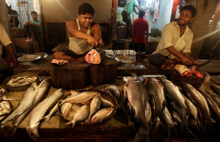 Fish sellers cut fish for customers at a market in Gauhati, India, Friday, May 30, 2014. India on Friday reported economic growth of 4.7 percent for the last fiscal year, falling short of the government's forecast and continuing a trend of sluggish expansion that helped sweep a new government to power this month. (AP Photo/Anupam Nath)