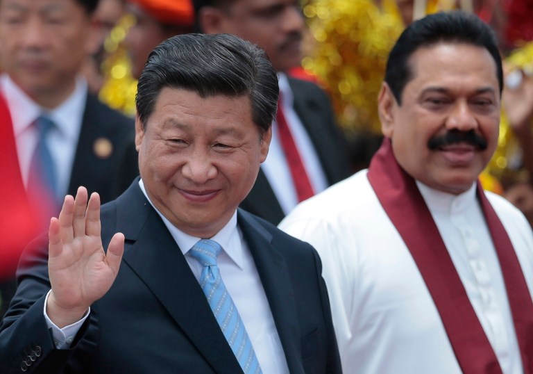 China's President Xi Jinping, left, waves to the gathering as he walks with Sri Lankan President Mahinda Rajapaksa upon arrival at the airport in Colombo, Sri Lanka, Tuesday, Sept. 16, 2014. (AP Photo/Eranga Jayawardena)