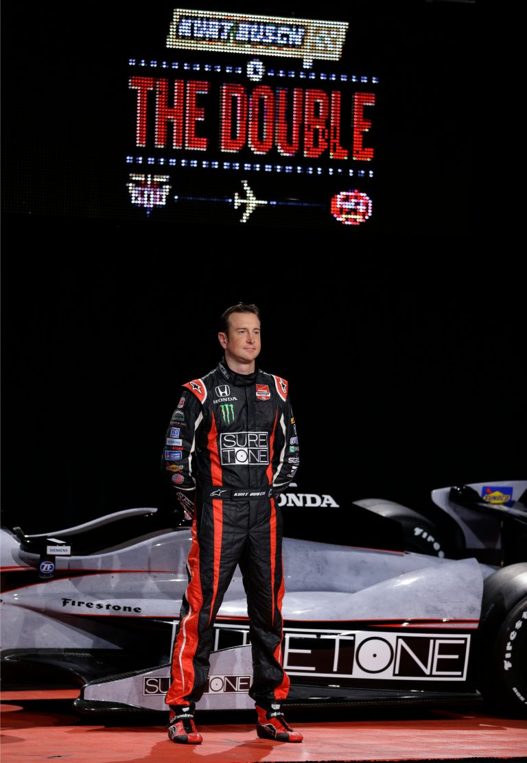 NASCAR driver Kurt Busch stands in front of his newly unveiled IndyCar entry for the Indianapolis 500 during an announcement in Indianapolis, Monday, April 28, 2014. Busch will try to be the first driver in a decade to compete in IndyCar's Indianapolis 500 and Sprint Cup's Coca-Cola 600 on the same day. (AP Photo/Michael Conroy)