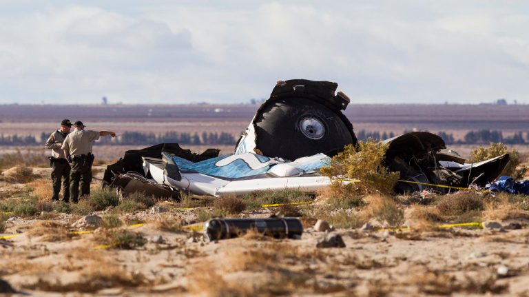 Law enforcement officers take a closer look at the wreckage near the site where a Virgin Galactic space tourism rocket, SpaceShipTwo, exploded and crashed in Mojave, Calif. Saturday. The explosion killed a pilot aboard and seriously injured another while scattering wreckage in Southern California's Mojave Desert, witnesses and officials said. (AP Photo/Ringo H.W. Chiu)