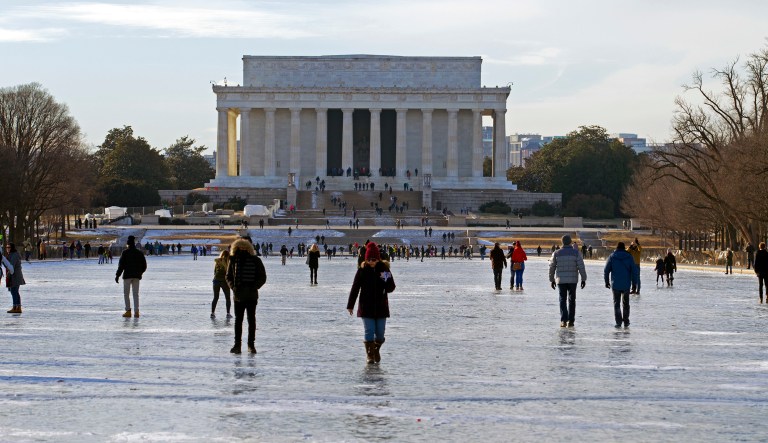 People walk one the frozen Reflecting Pool at the National Mall. The Energy Department has said the need to address grid reliability and resilience was punctuated by the two-week cold snap, which ended with the 